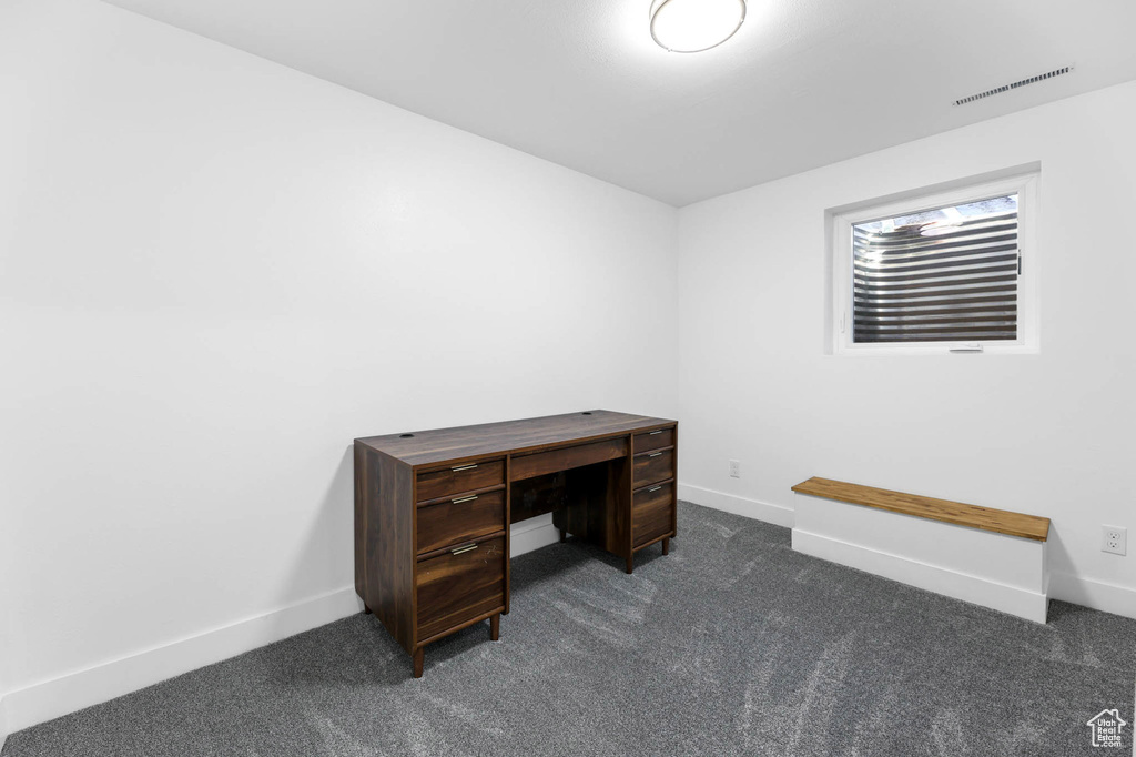 Unfurnished office featuring dark colored carpet and baseboards