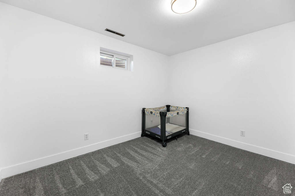 Spare room featuring dark colored carpet and baseboards