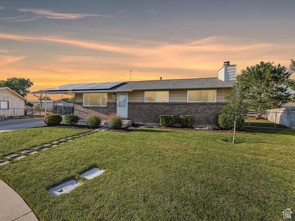 View of front of house with brick siding, roof mounted solar panels, a chimney, and concrete driveway