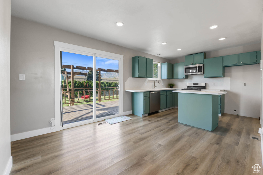Kitchen with green cabinets, appliances with stainless steel finishes, light countertops, light wood finished floors, and recessed lighting