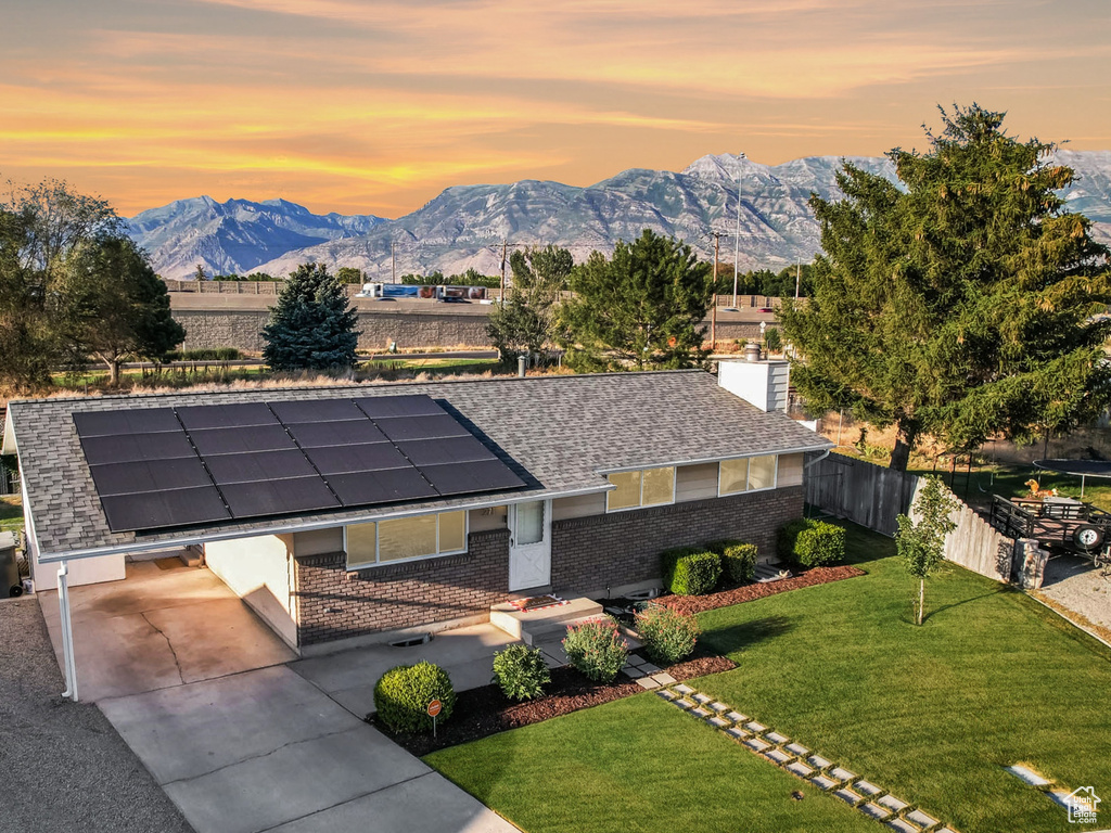 View of front of house featuring a mountain view, solar panels, brick siding, a chimney, and a shingled roof