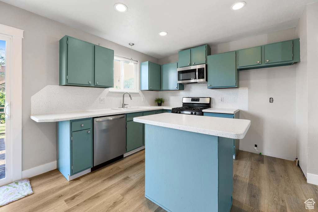 Kitchen featuring appliances with stainless steel finishes, light wood-style floors, light countertops, a center island, and recessed lighting