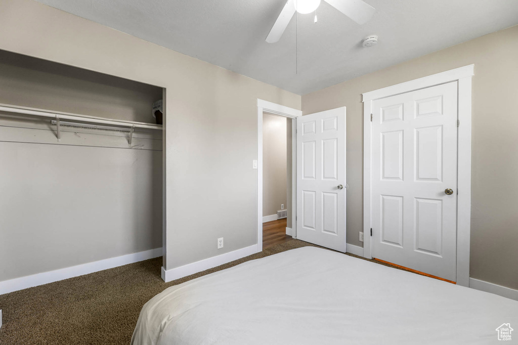 Bedroom with a closet, dark carpet, and ceiling fan
