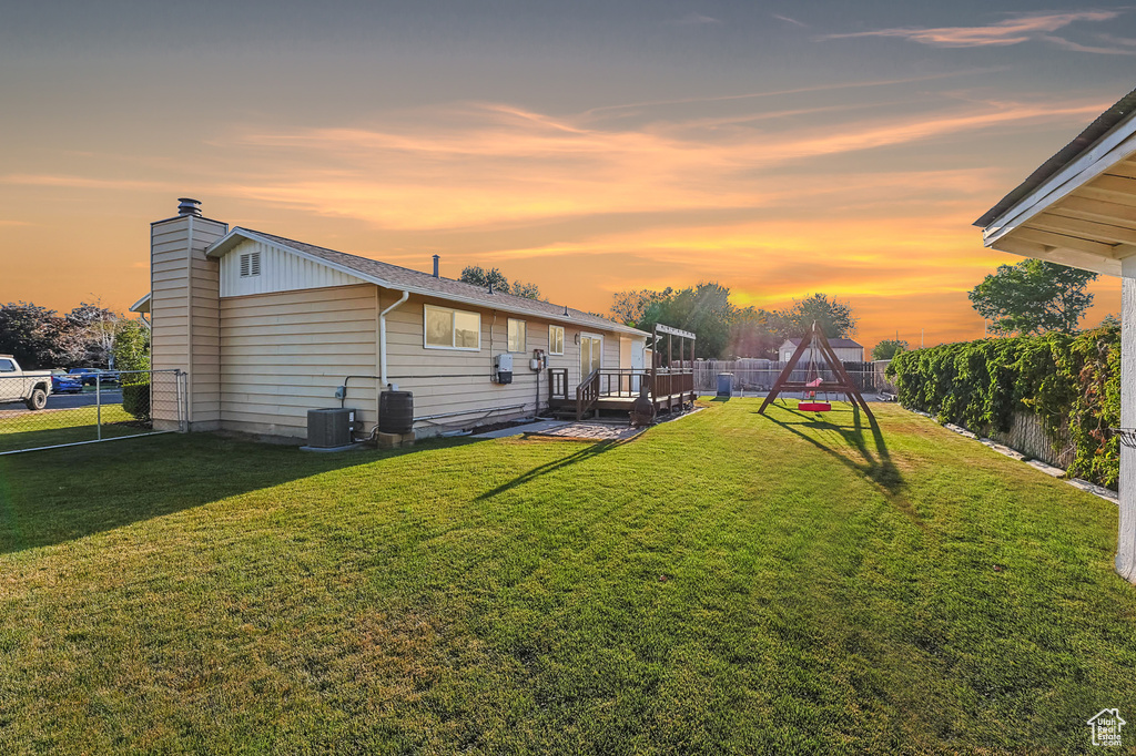 Yard at dusk featuring a fenced backyard and a deck