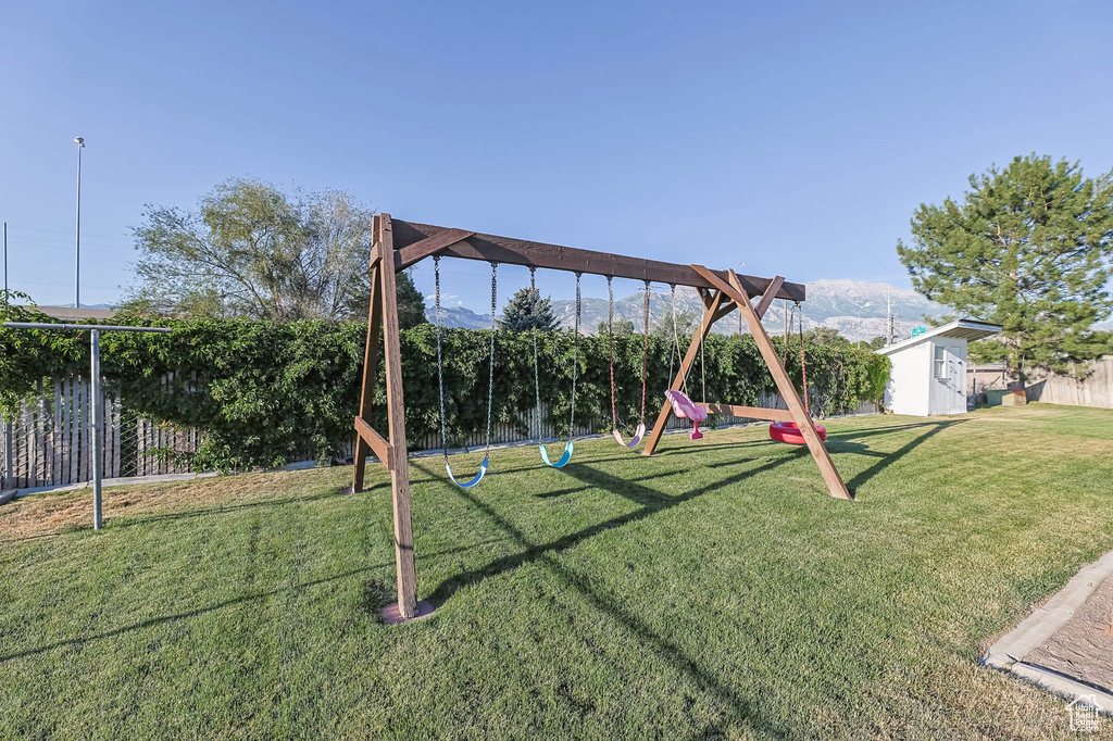 View of yard with a playground, a mountain view, and a shed