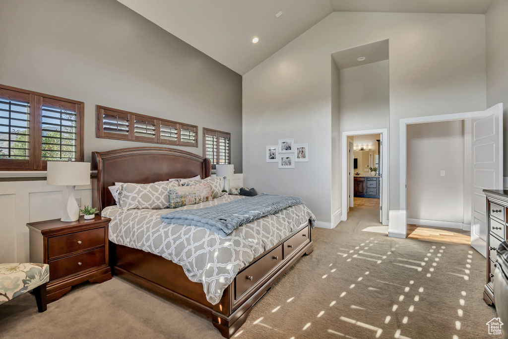 Carpeted bedroom featuring high vaulted ceiling and multiple windows