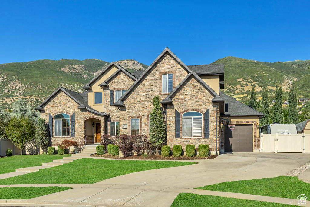 Craftsman inspired home featuring a gate, concrete driveway, a mountain view, an attached garage, and a shingled roof