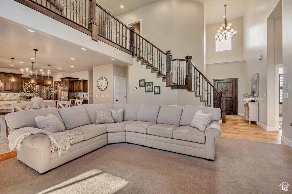 Living area with a high ceiling, a chandelier, recessed lighting, stairs, and light wood-type flooring