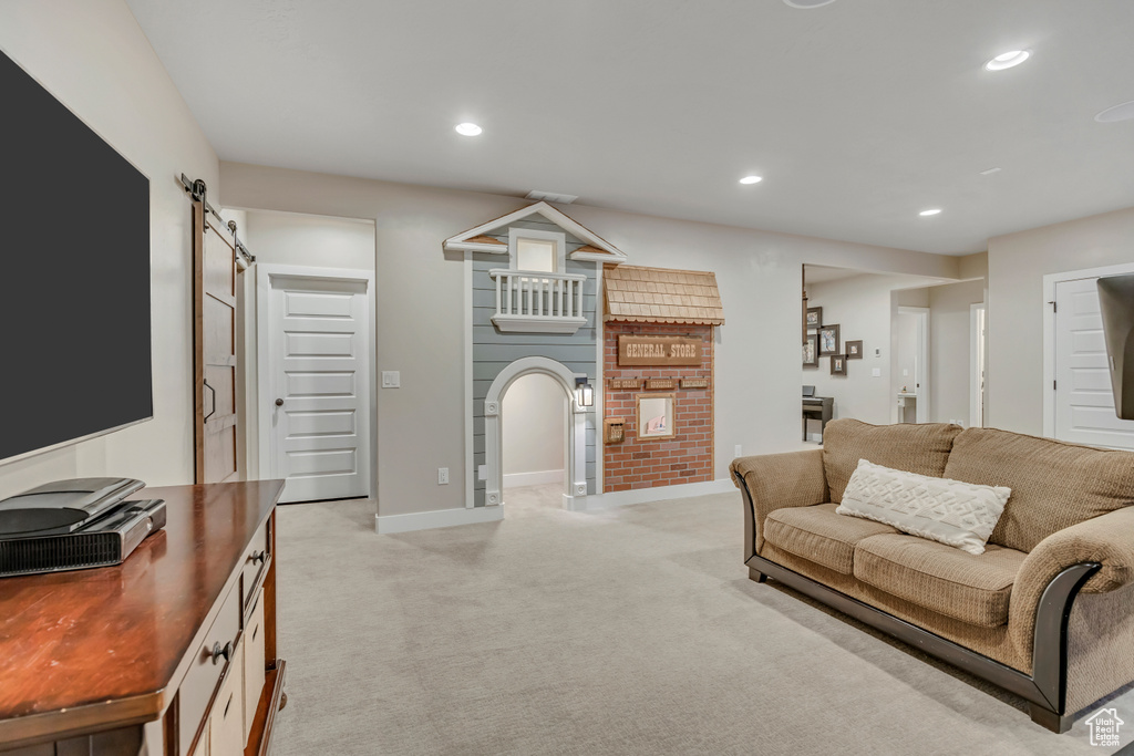 Living room with a barn door, light colored carpet, recessed lighting, and arched walkways