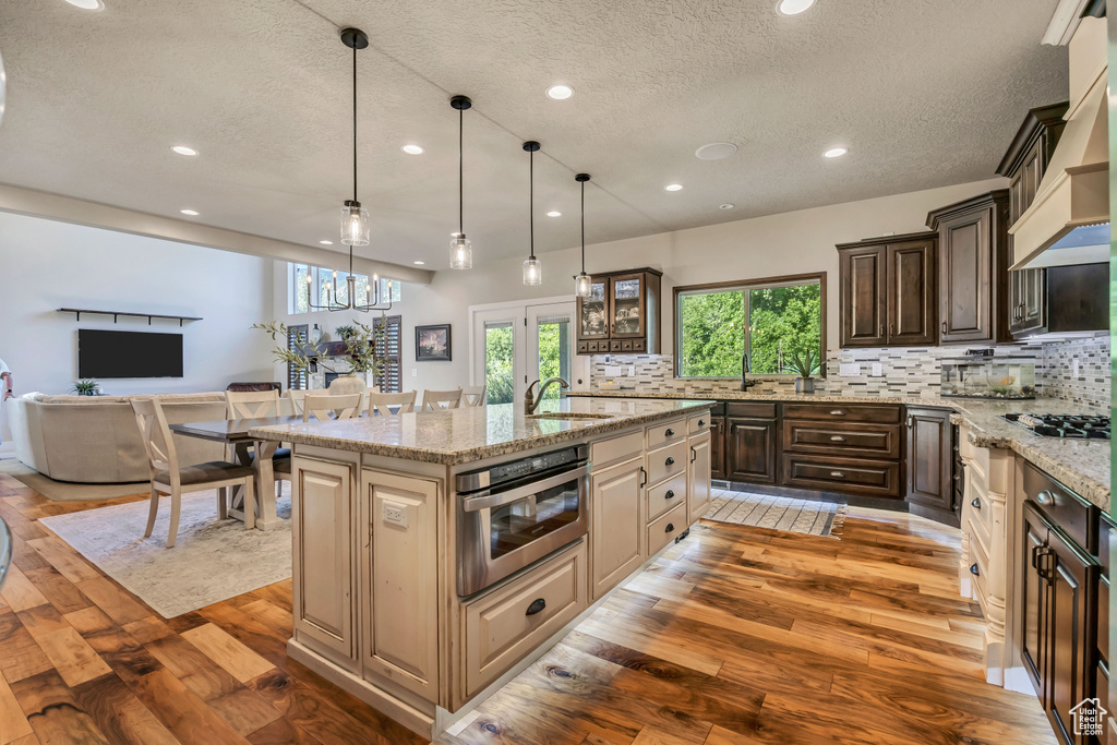 Kitchen with light wood-type flooring, a textured ceiling, stainless steel appliances, recessed lighting, and backsplash