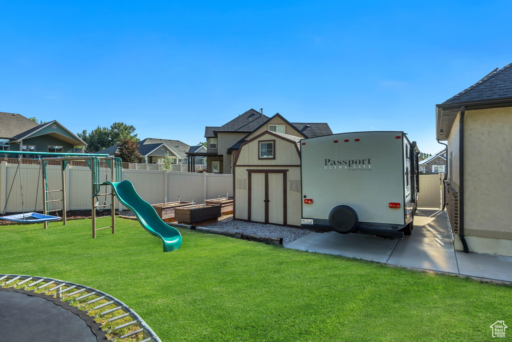 View of jungle gym featuring a fenced backyard, a shed, and a residential view
