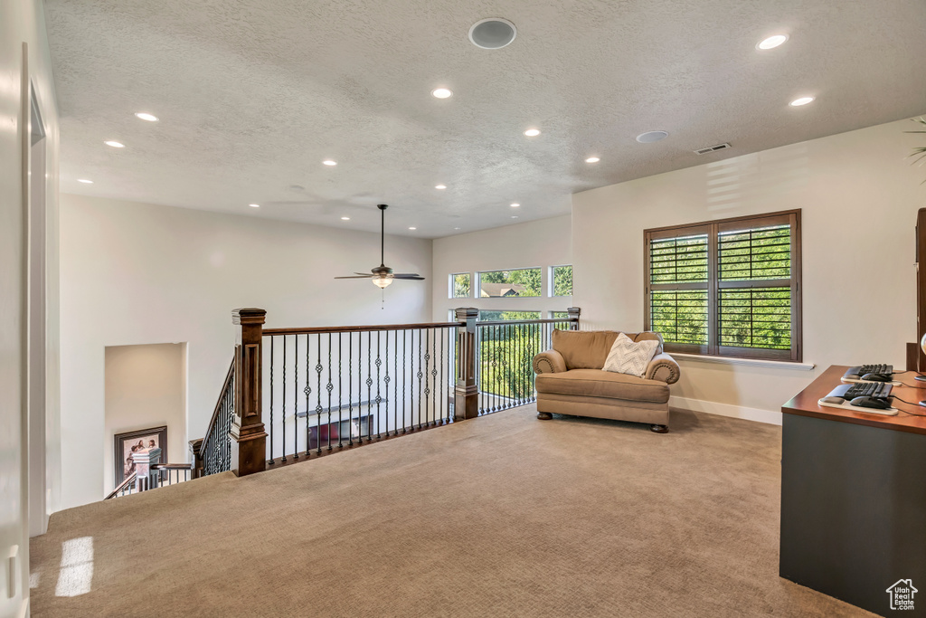 Living area with recessed lighting, carpet flooring, ceiling fan, a textured ceiling, and an upstairs landing