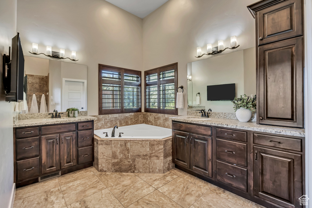 Bathroom with vanity, a garden tub, tile patterned floors, and a high ceiling