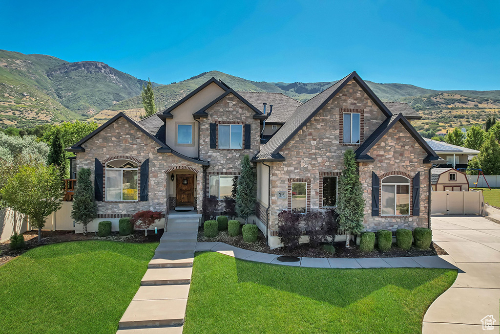 View of front of home featuring stone siding, a mountain view, and driveway