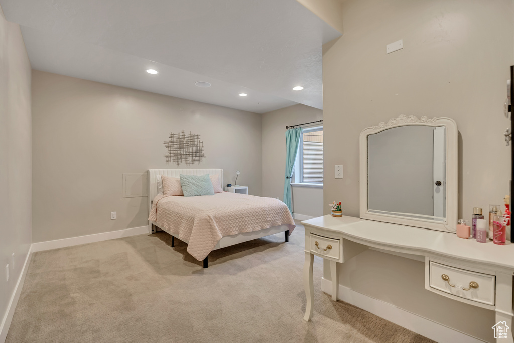 Bedroom with light colored carpet, recessed lighting, and an office area