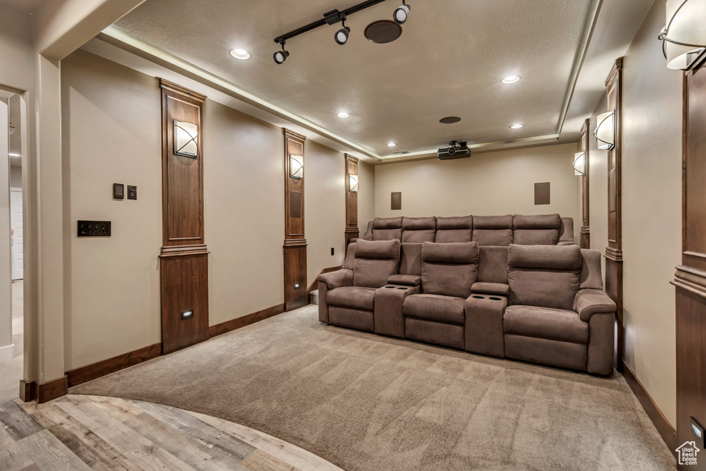 Cinema room with a tray ceiling, recessed lighting, carpet floors, and wood finished floors