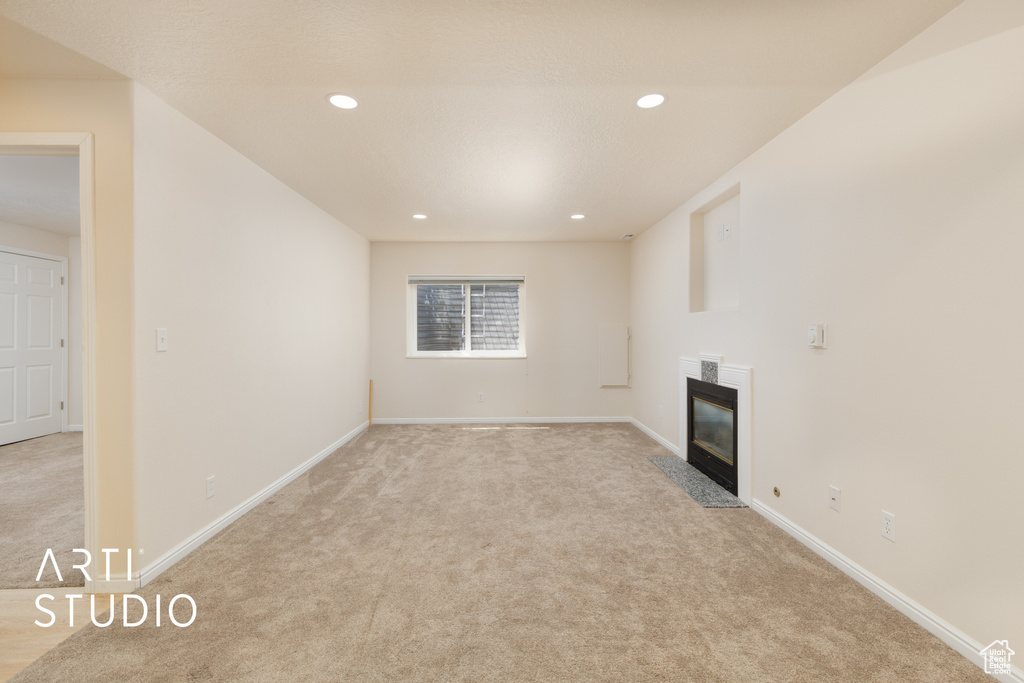 Unfurnished living room featuring light colored carpet, a fireplace, and recessed lighting