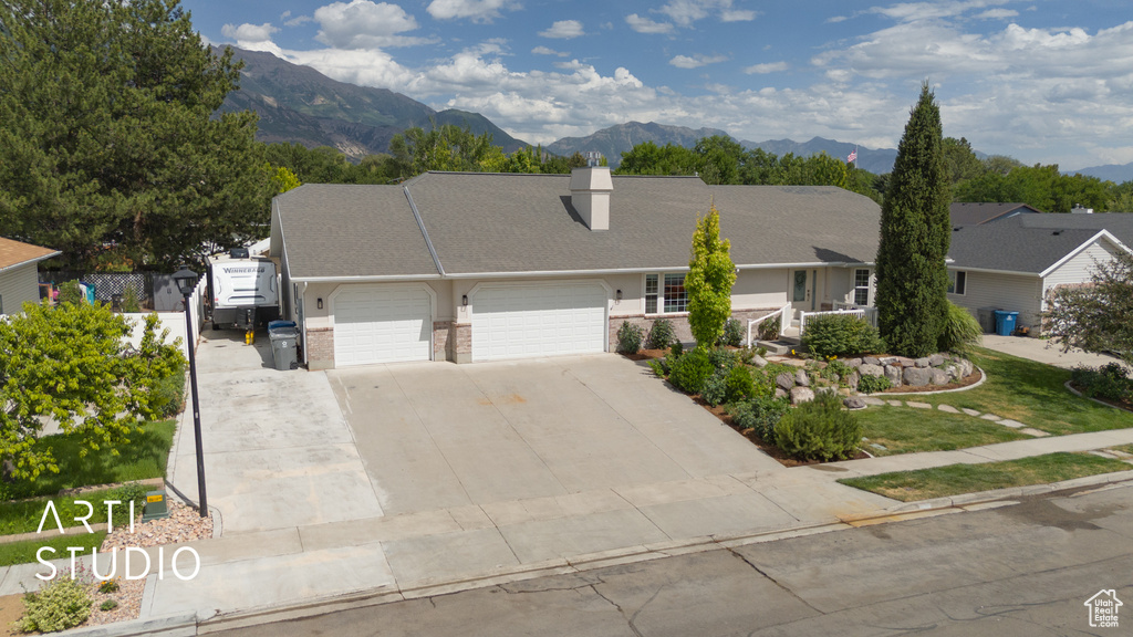 View of front of property with an attached garage, a chimney, concrete driveway, a mountain view, and brick siding