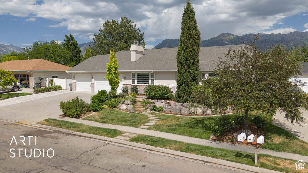View of front of property featuring a garage, driveway, a mountain view, and a chimney