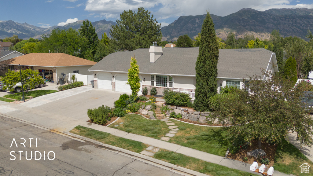 View of front facade featuring an attached garage, driveway, a chimney, and a mountain view