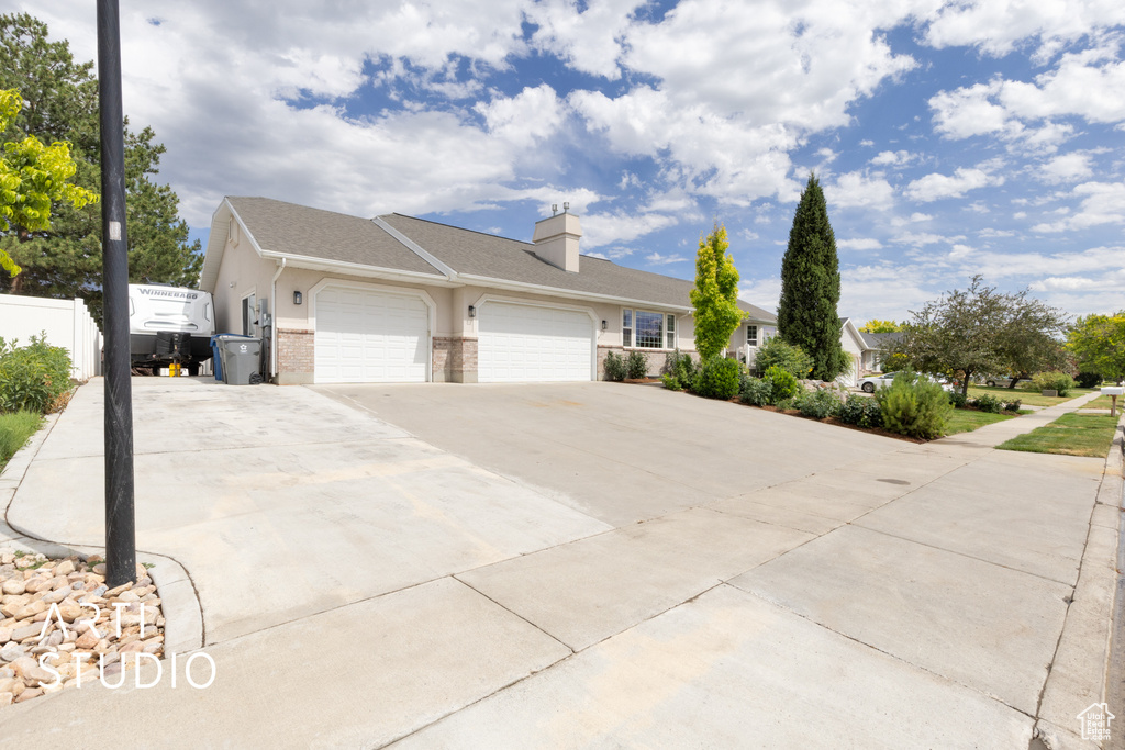 View of side of home with a garage, concrete driveway, brick siding, and a chimney
