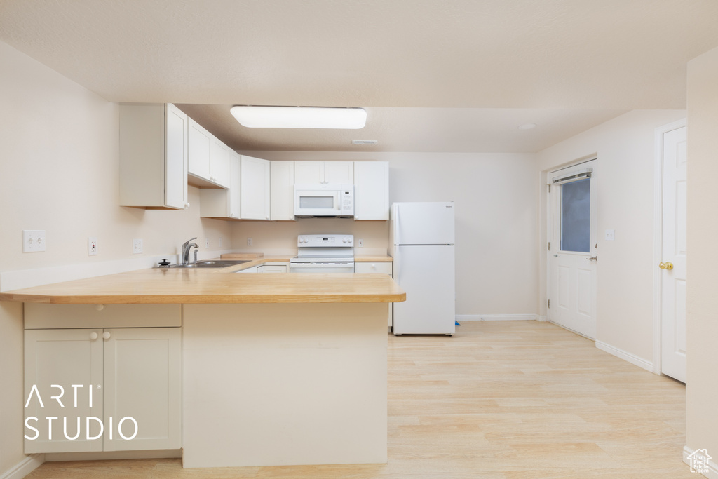 Kitchen featuring white appliances, a peninsula, light wood-style flooring, wooden counters, and white cabinetry