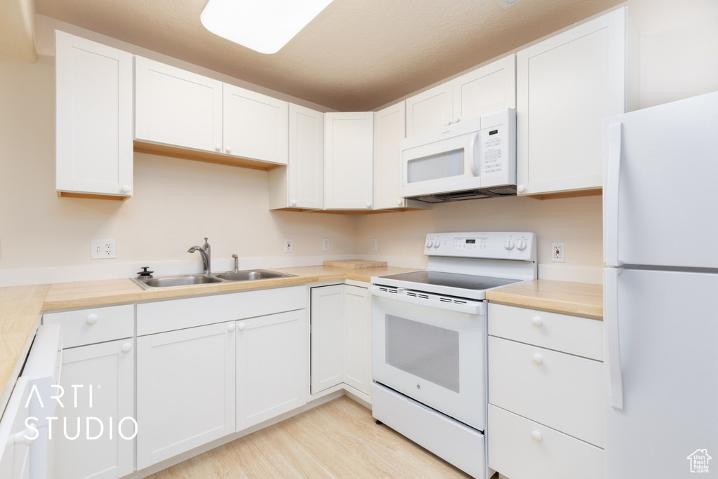 Kitchen featuring white appliances, white cabinetry, and light wood finished floors