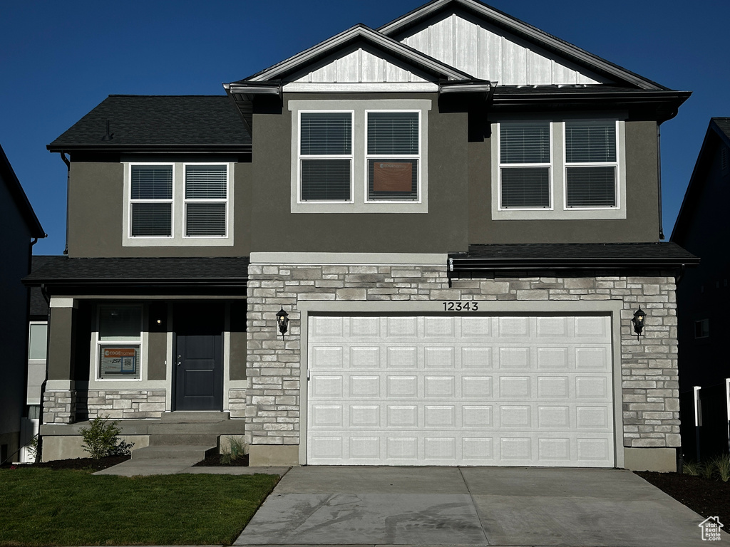 Craftsman-style home featuring stone siding, driveway, and stucco siding