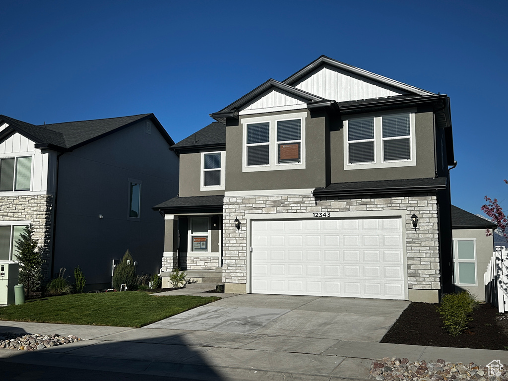 Craftsman-style home with stone siding, driveway, an attached garage, and stucco siding