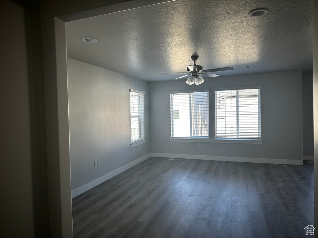 Empty room featuring dark wood-style flooring, ceiling fan, and a textured ceiling