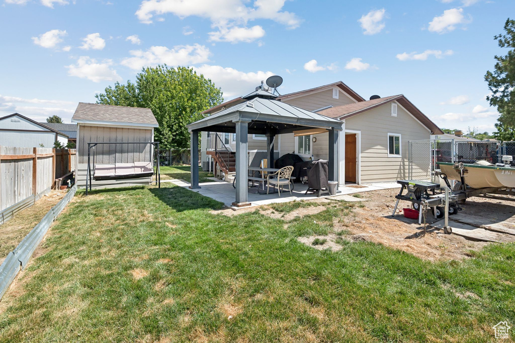 Rear view of property featuring a patio, a gazebo, a fenced backyard, and a storage shed