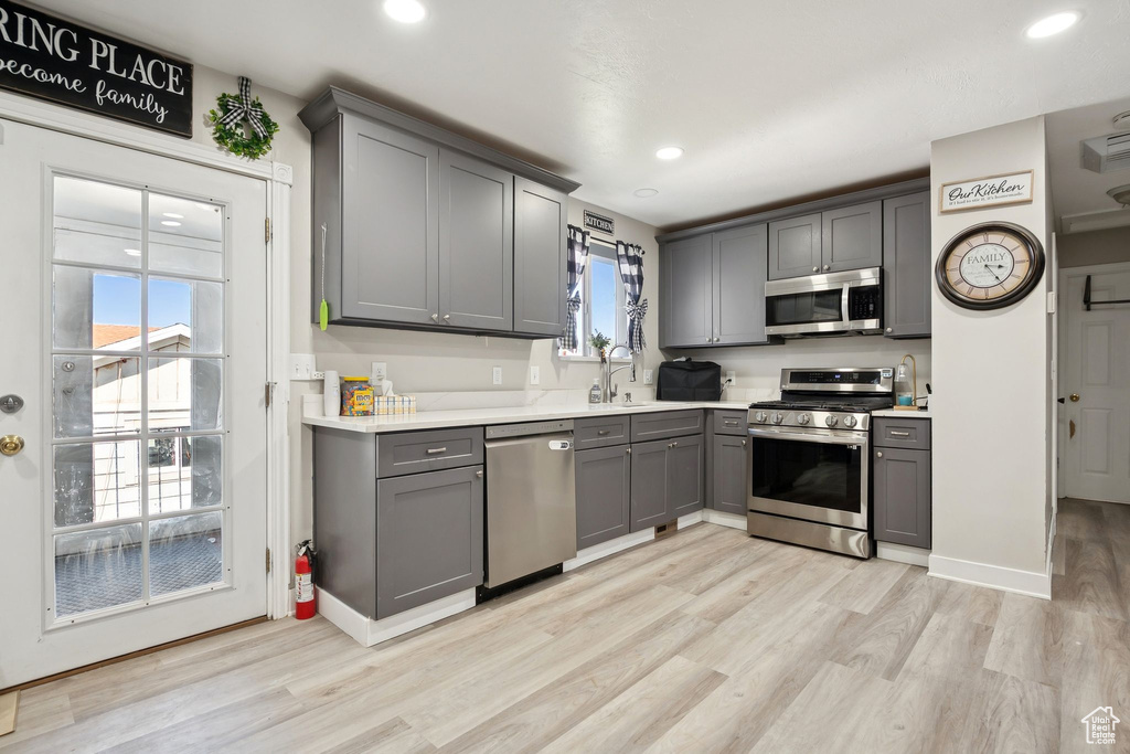 Kitchen featuring stainless steel appliances, gray cabinetry, light wood-style flooring, light countertops, and recessed lighting
