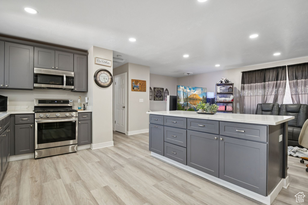 Kitchen featuring appliances with stainless steel finishes, gray cabinetry, light countertops, light wood-type flooring, and recessed lighting
