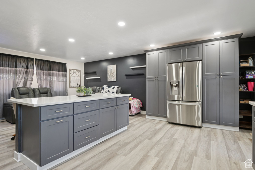 Kitchen featuring stainless steel refrigerator with ice dispenser, gray cabinetry, light countertops, light wood finished floors, and recessed lighting