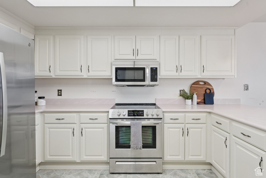 Kitchen featuring appliances with stainless steel finishes, light countertops, and white cabinetry