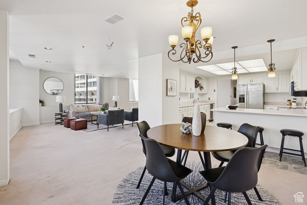 Dining space featuring light colored carpet and a chandelier