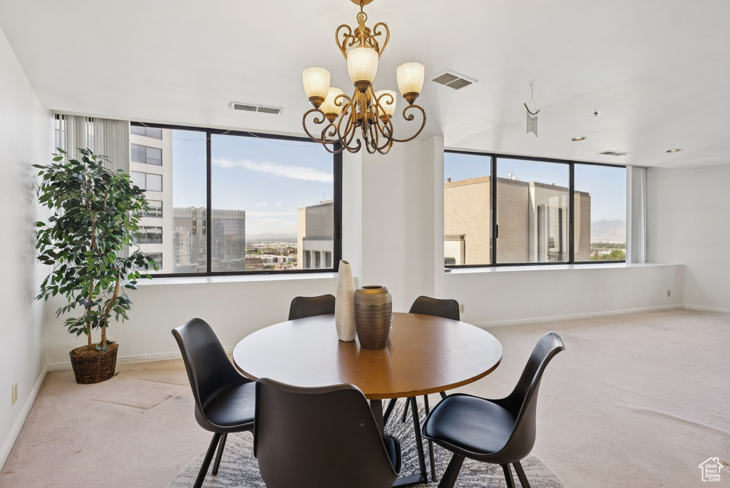 Carpeted dining space featuring a chandelier and baseboards