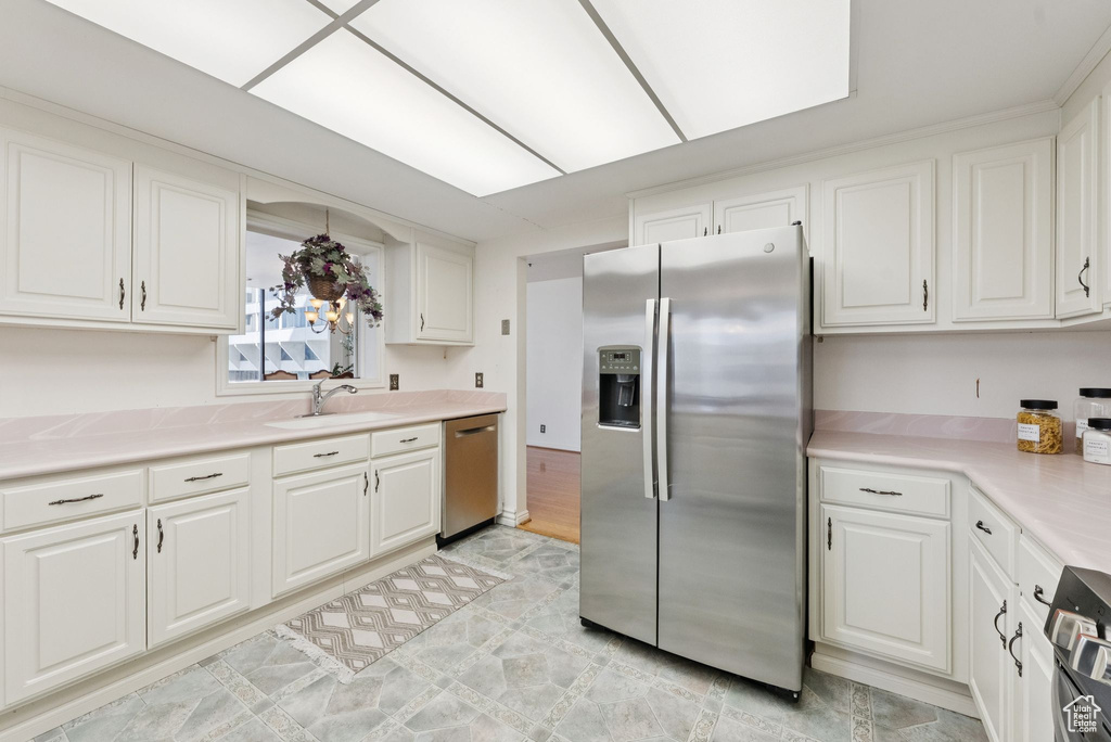 Kitchen with appliances with stainless steel finishes, white cabinetry, and light countertops