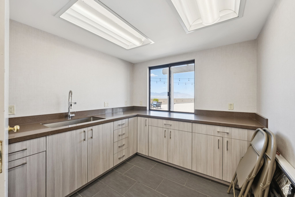 Kitchen featuring dark countertops, dark tile patterned floors, and light brown cabinetry