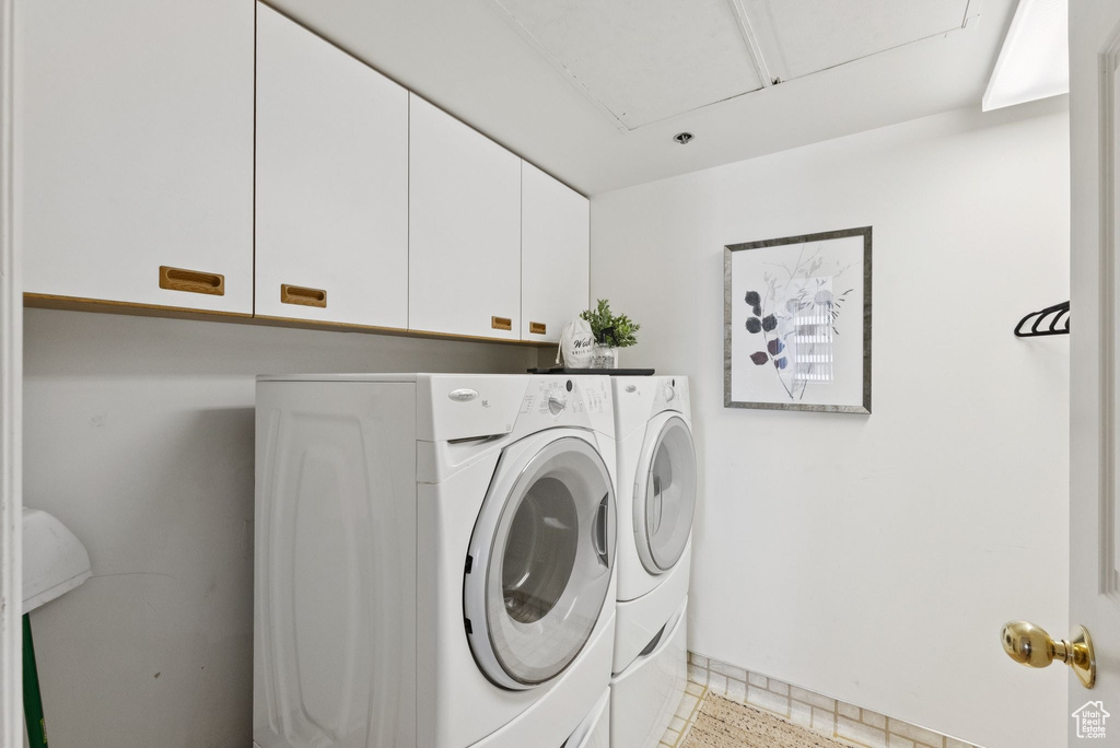 Laundry area with cabinet space, separate washer and dryer, and attic access