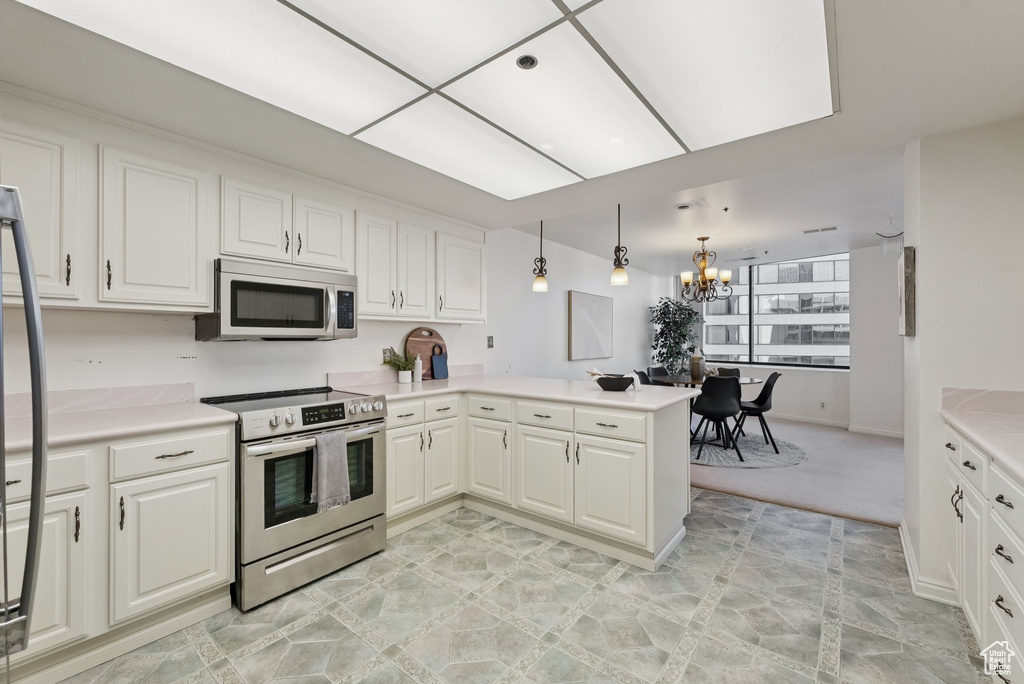 Kitchen featuring stainless steel appliances, a chandelier, a peninsula, and white cabinets