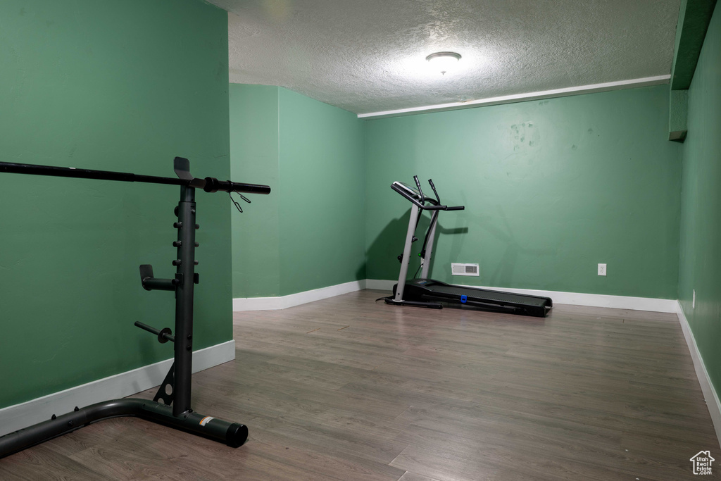 Exercise area with a textured ceiling and wood finished floors
