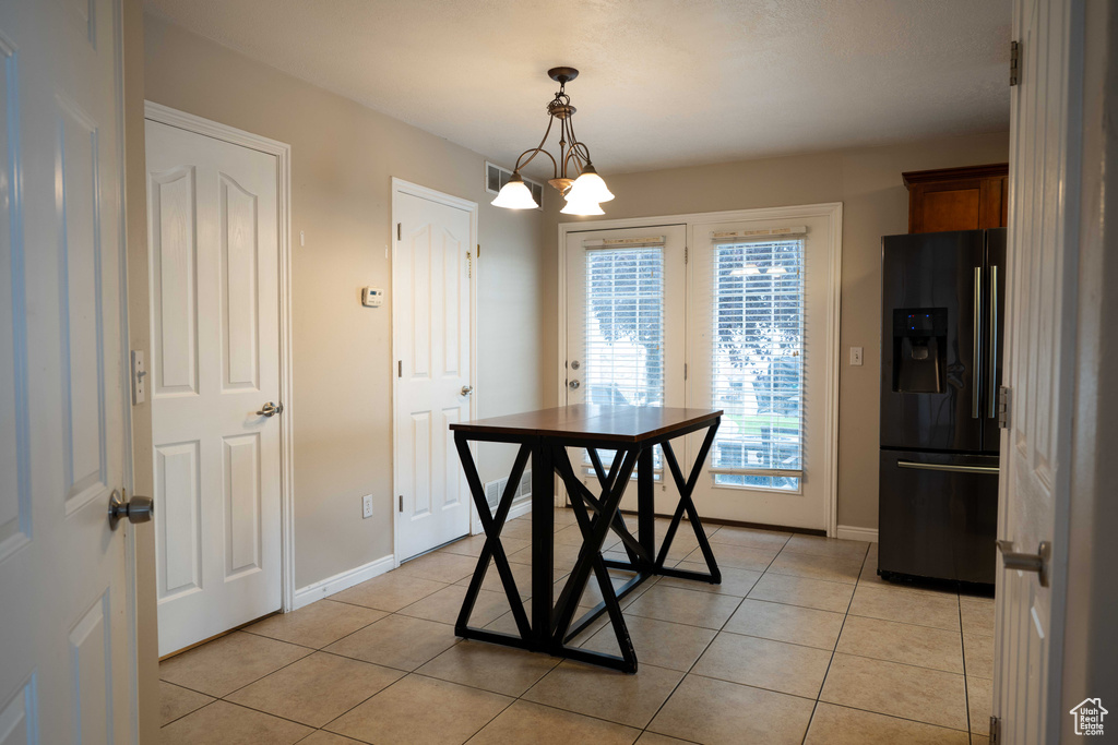Unfurnished dining area featuring a chandelier and light tile patterned floors