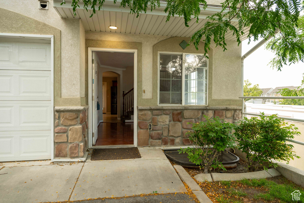 Entrance to property with stone siding, stucco siding, and a garage