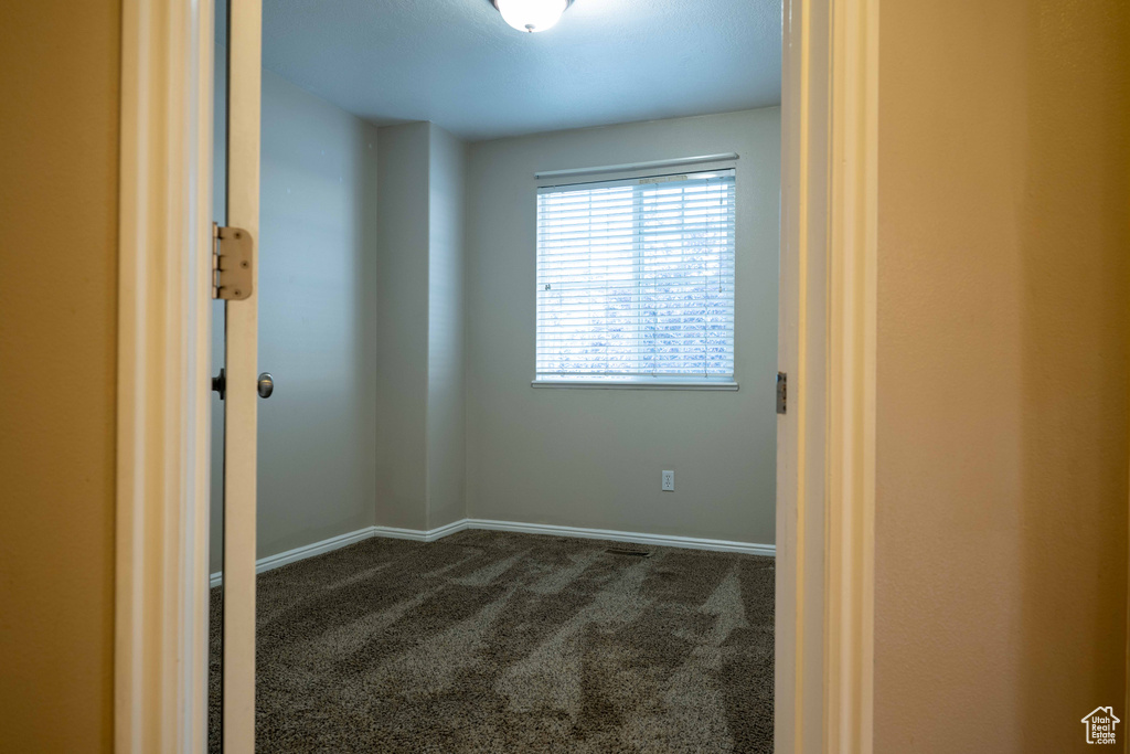 Empty room with dark colored carpet and baseboards