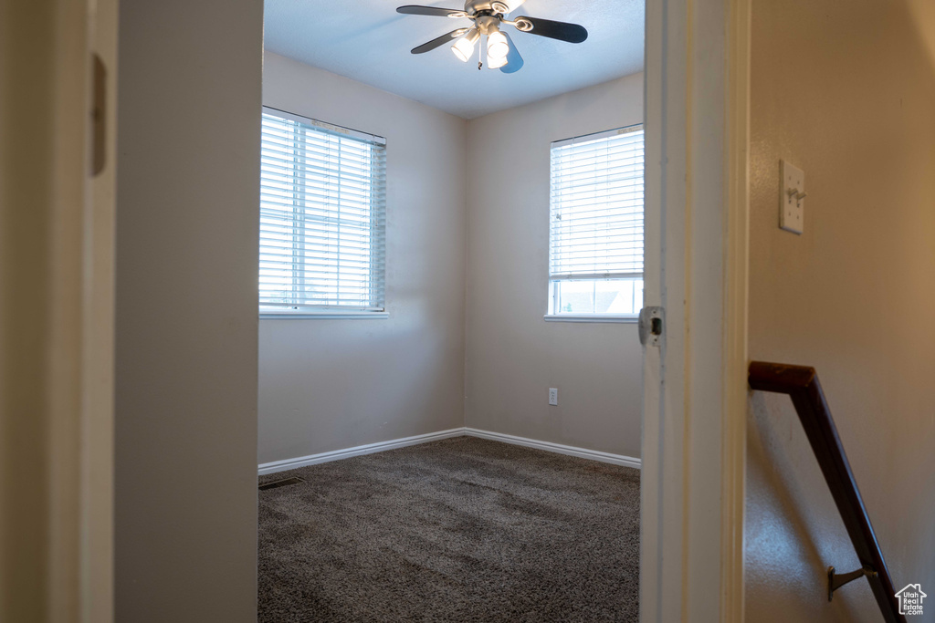 Carpeted empty room featuring a ceiling fan and baseboards