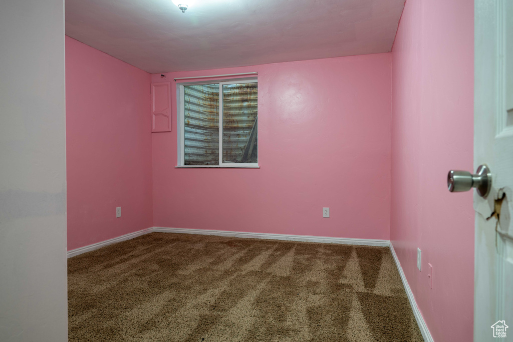 Carpeted spare room featuring baseboards