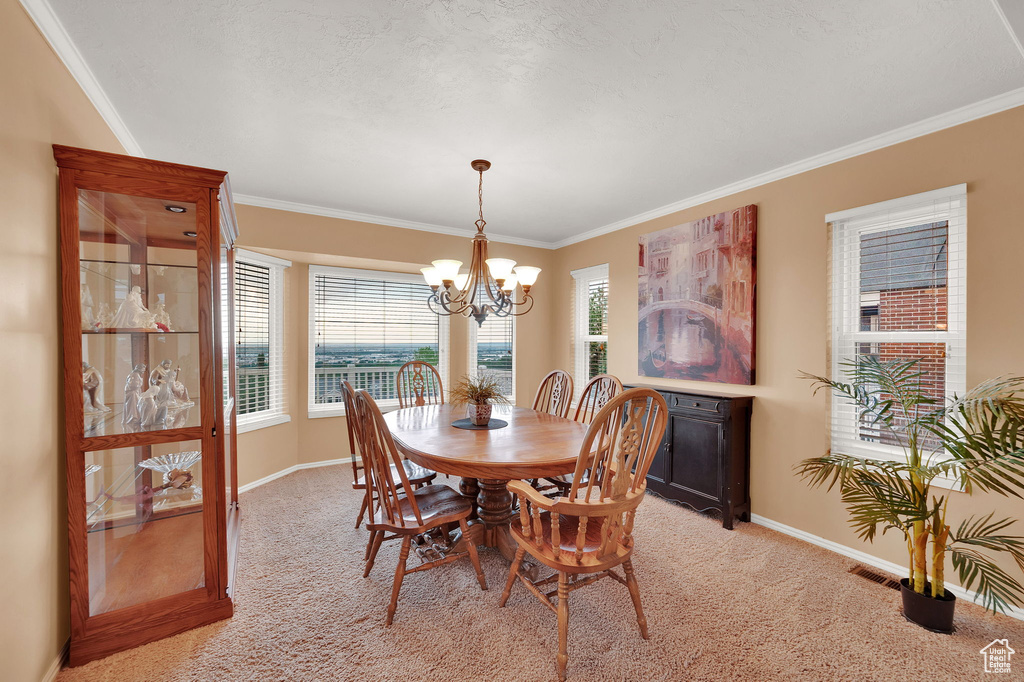 Dining space featuring crown molding, light carpet, and a chandelier