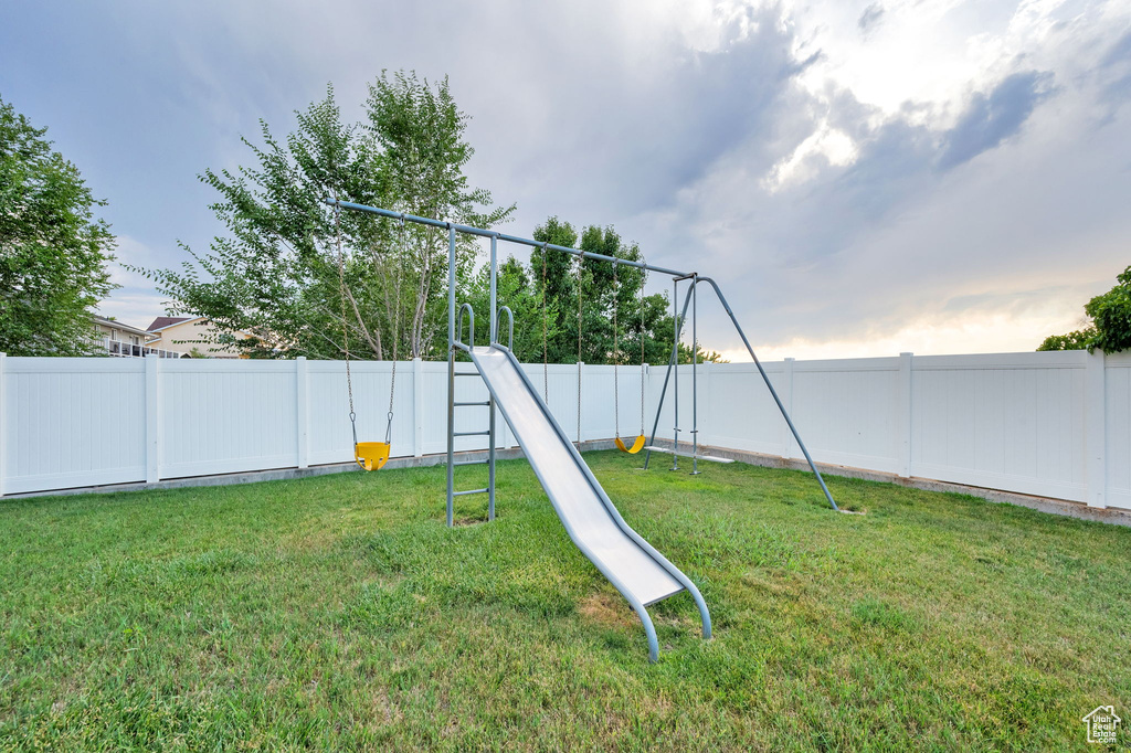 Fenced backyard featuring a playground