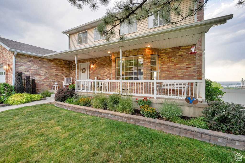 Traditional home with covered porch, brick siding, and a front lawn